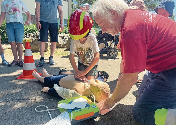 Dieser Junge vollführt unter Anleitung des Profis eine Herzmassage an der Kinderpuppe.