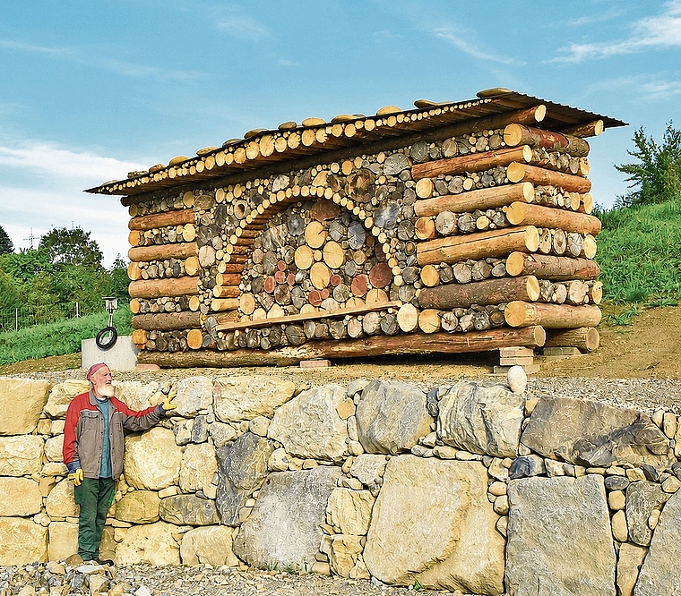 Gartengestalter Ruedi Lüthi vor seinem jüngsten Werk: Die Trockenmauer mit dem kunstvoll geschichteten Holz soll auf dem Gelände der ehemaligen Sondermülldeponie neuen Lebensraum für Vögel, Insekten, Amphibien und Kleinsäuger bieten.Bild: Frie